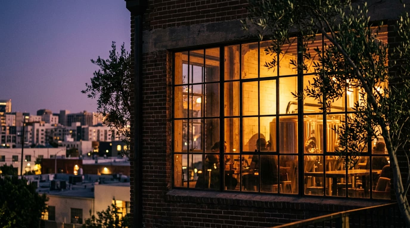 A 100mm macro shot captures the warm, tungsten glow spilling from the industrial-chic windows of a Torrance brewery, set a...